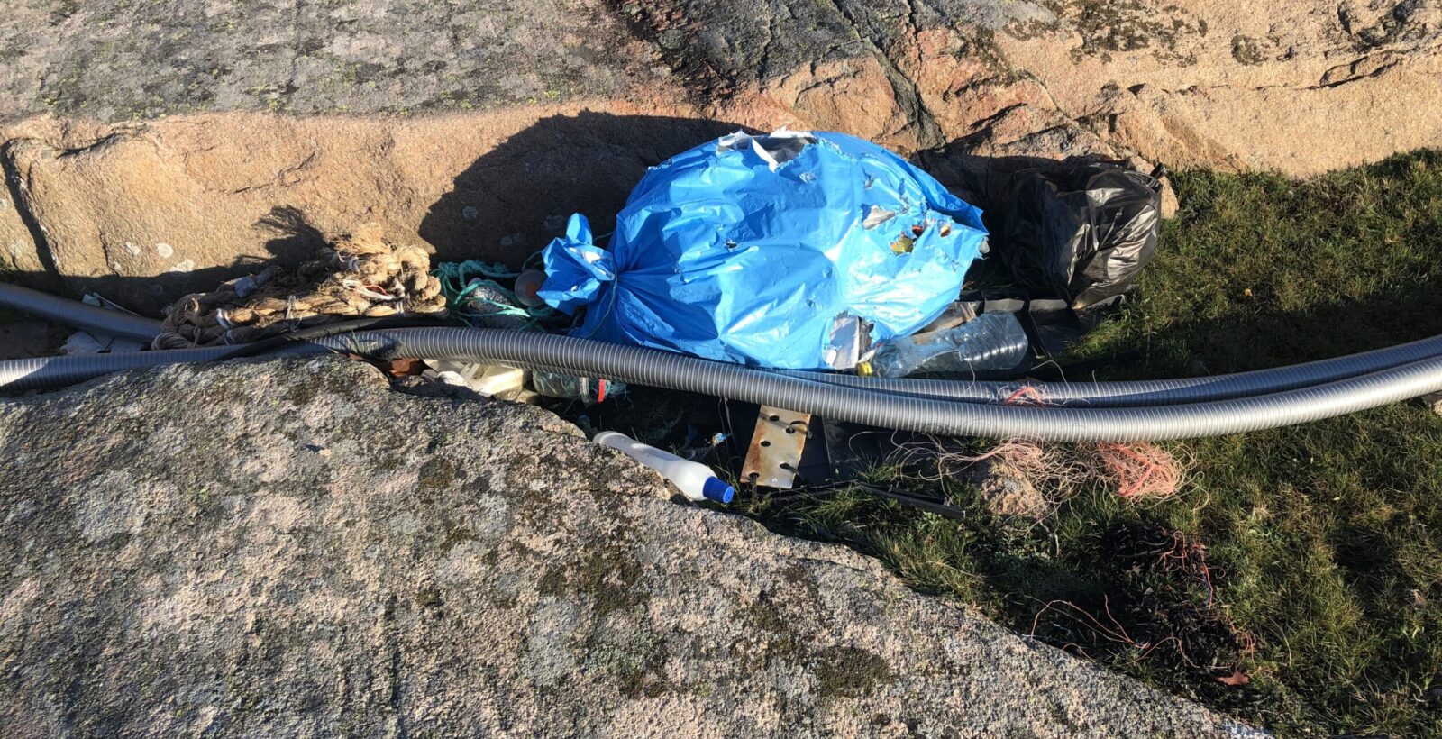 Marint skräp, främst plast, i en klippskreva. Foto.