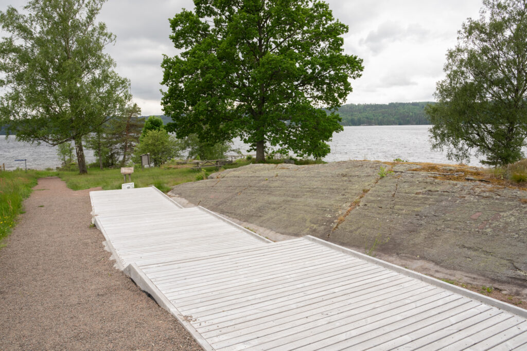 Grusad stig och spång, som sträcker sig parallellt med en häll med hällristningar. Foto.