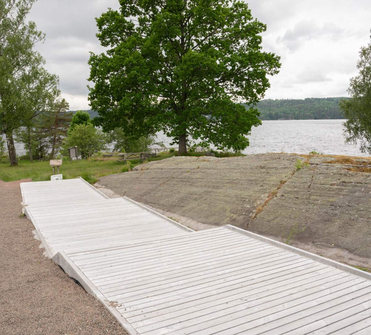 Grusad stig och spång, som sträcker sig parallellt med en häll med hällristningar. Foto.