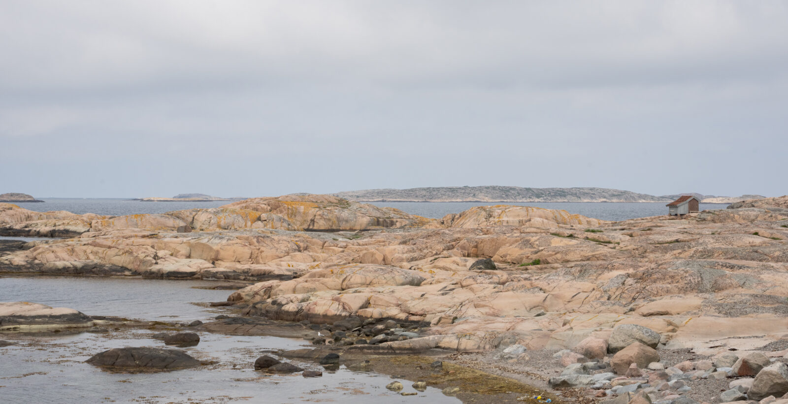 Klippor, hav och en liten bod. Foto.